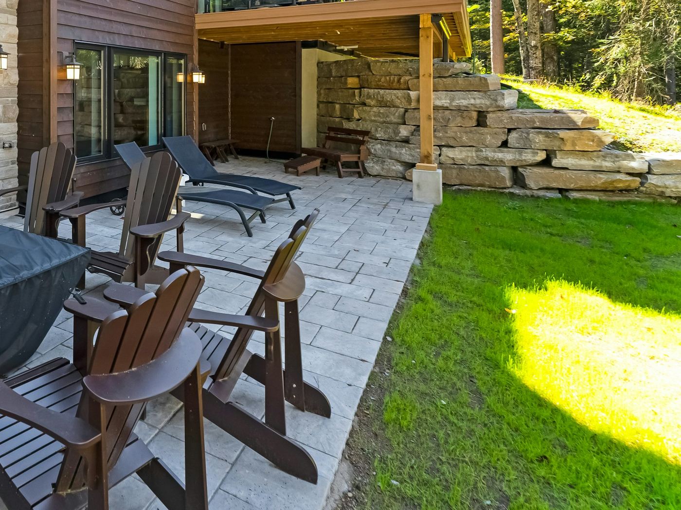 Boulder steps and a retaining wall beside a new lawn and a gray stone patio.